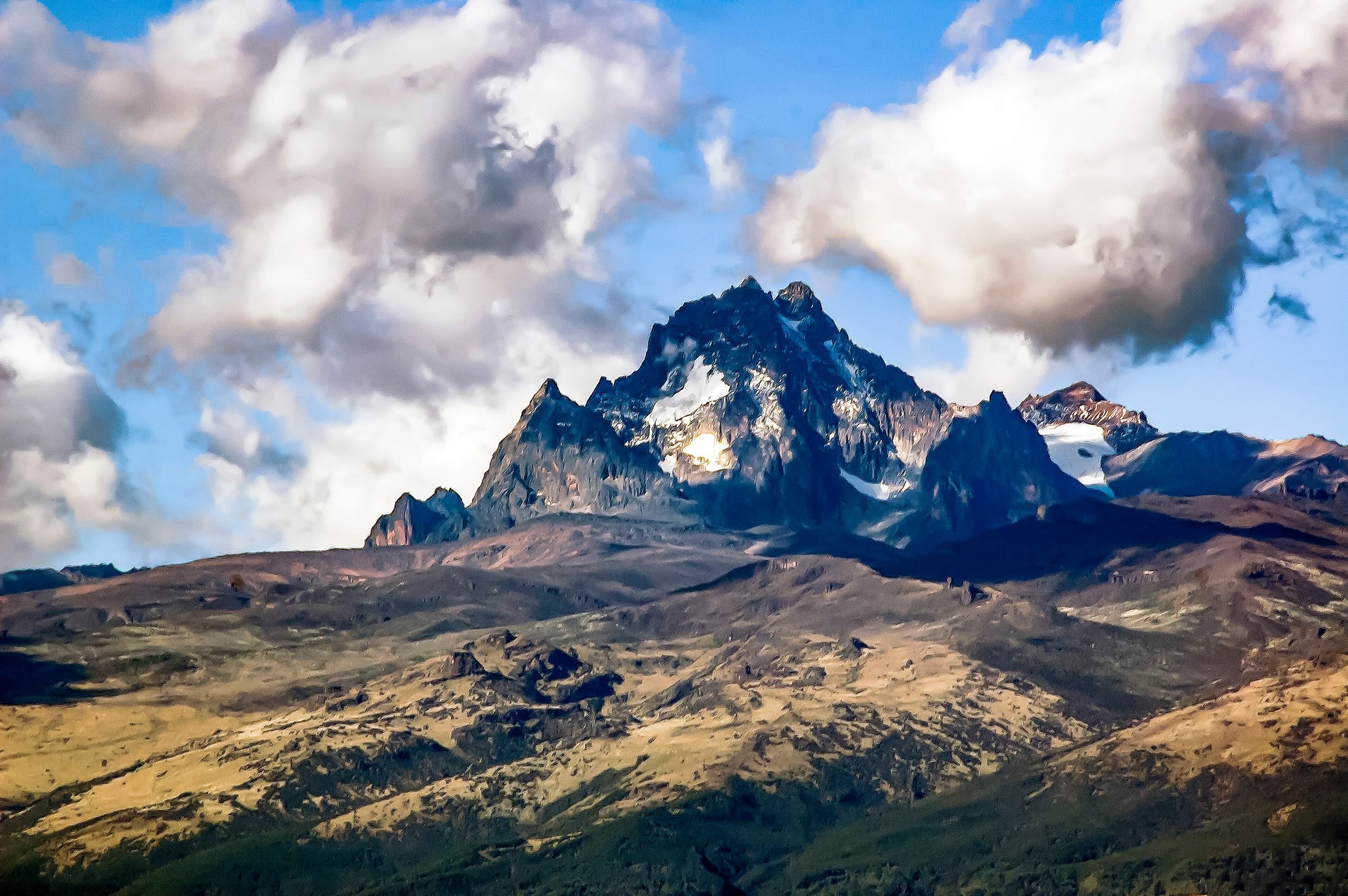 The jagged snow-streaked peaks of Mt. Kenya under a cloudy sky